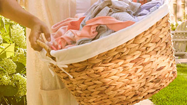 Imagen de una mujer levantando una cesta de ropa limpia. Descubre cómo Amway Home simplifica tu vida.